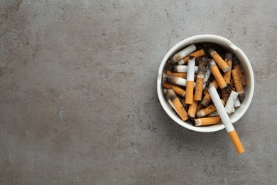 Ceramic ashtray with cigarette stubs on grey table, top view. Space for text