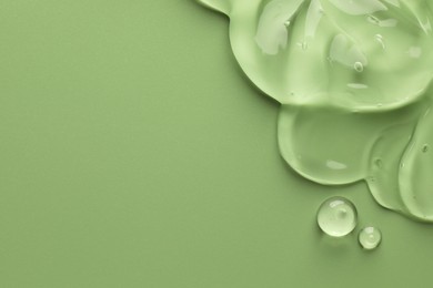 Clear cosmetic gel on light green background, top view. Space for text