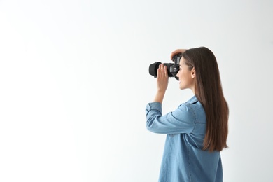 Female photographer with camera on light background