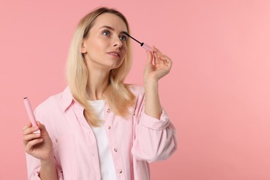 Photo of Beautiful woman with mascara on pink background, space for text