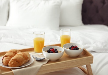 Photo of Tray with tasty breakfast on white bed