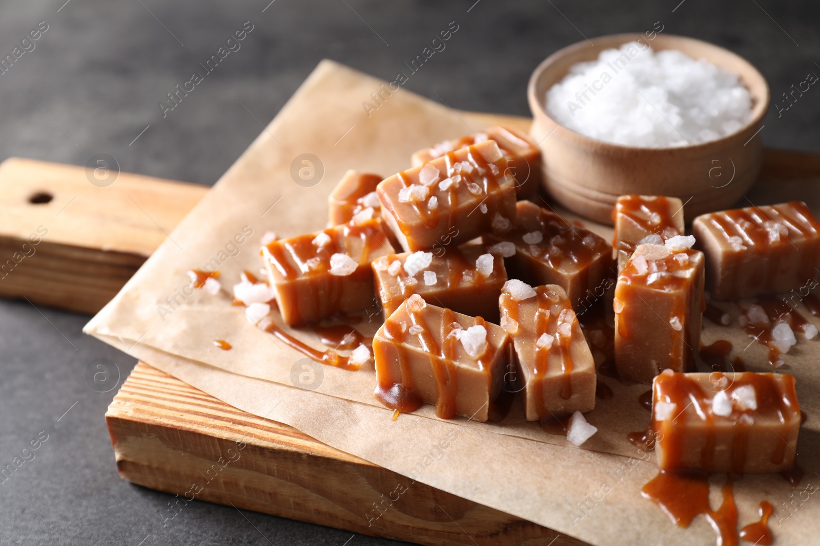 Photo of Tasty candies, caramel sauce and salt on grey table, closeup