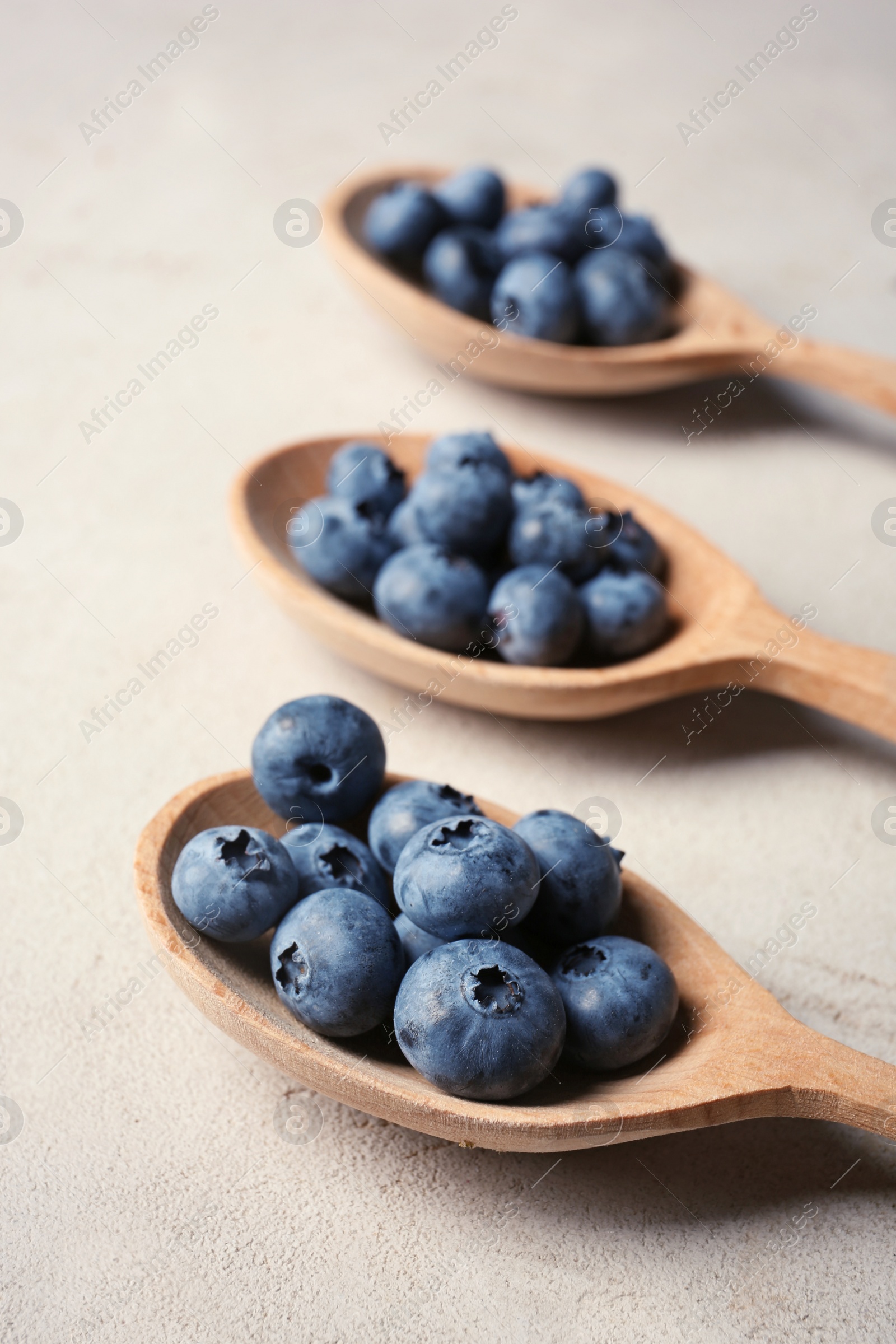 Photo of Wooden spoons and juicy blueberries on color table