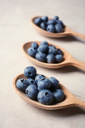 Wooden spoons and juicy blueberries on color table