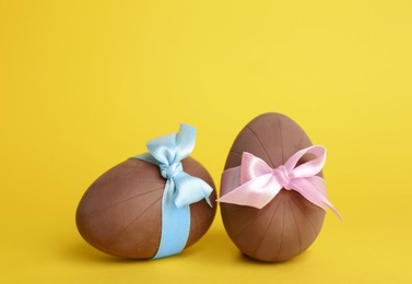 Two sweet chocolate eggs on yellow background