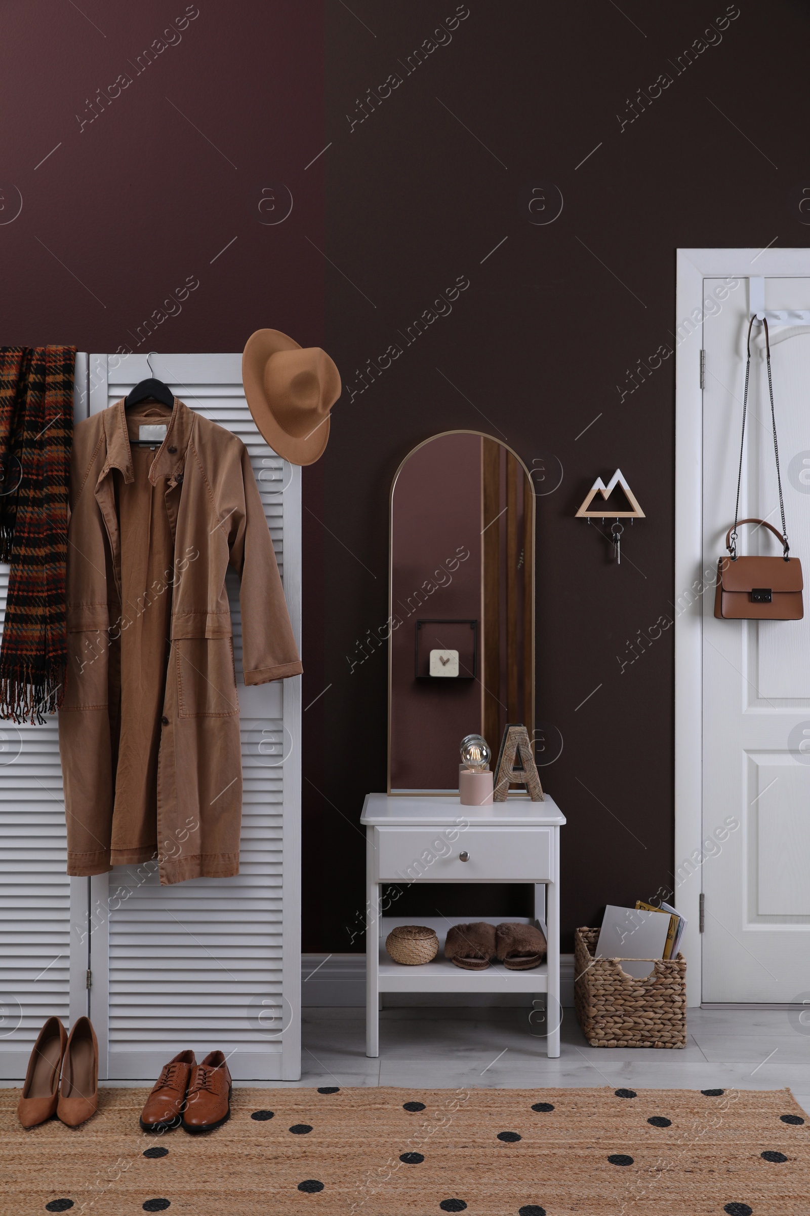 Photo of Modern hallway interior with stylish white furniture and wooden hanger for keys on brown wall