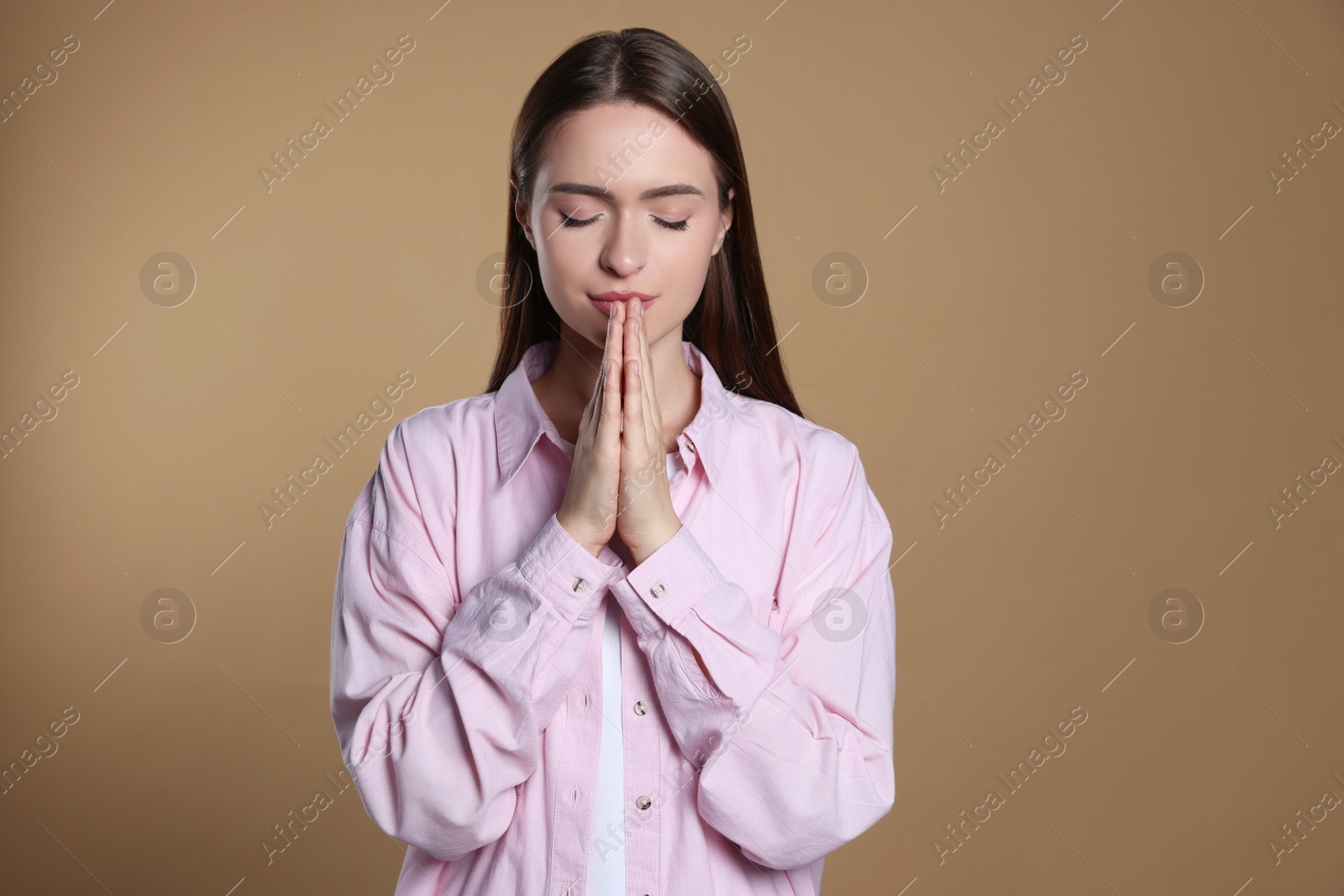 Photo of Woman with clasped hands praying on beige background