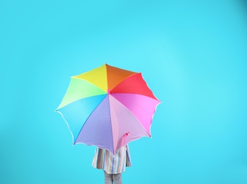 Little girl with rainbow umbrella on color background