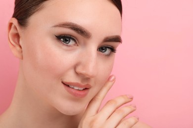 Makeup product. Woman with black eyeliner and beautiful eyebrows on pink background, closeup