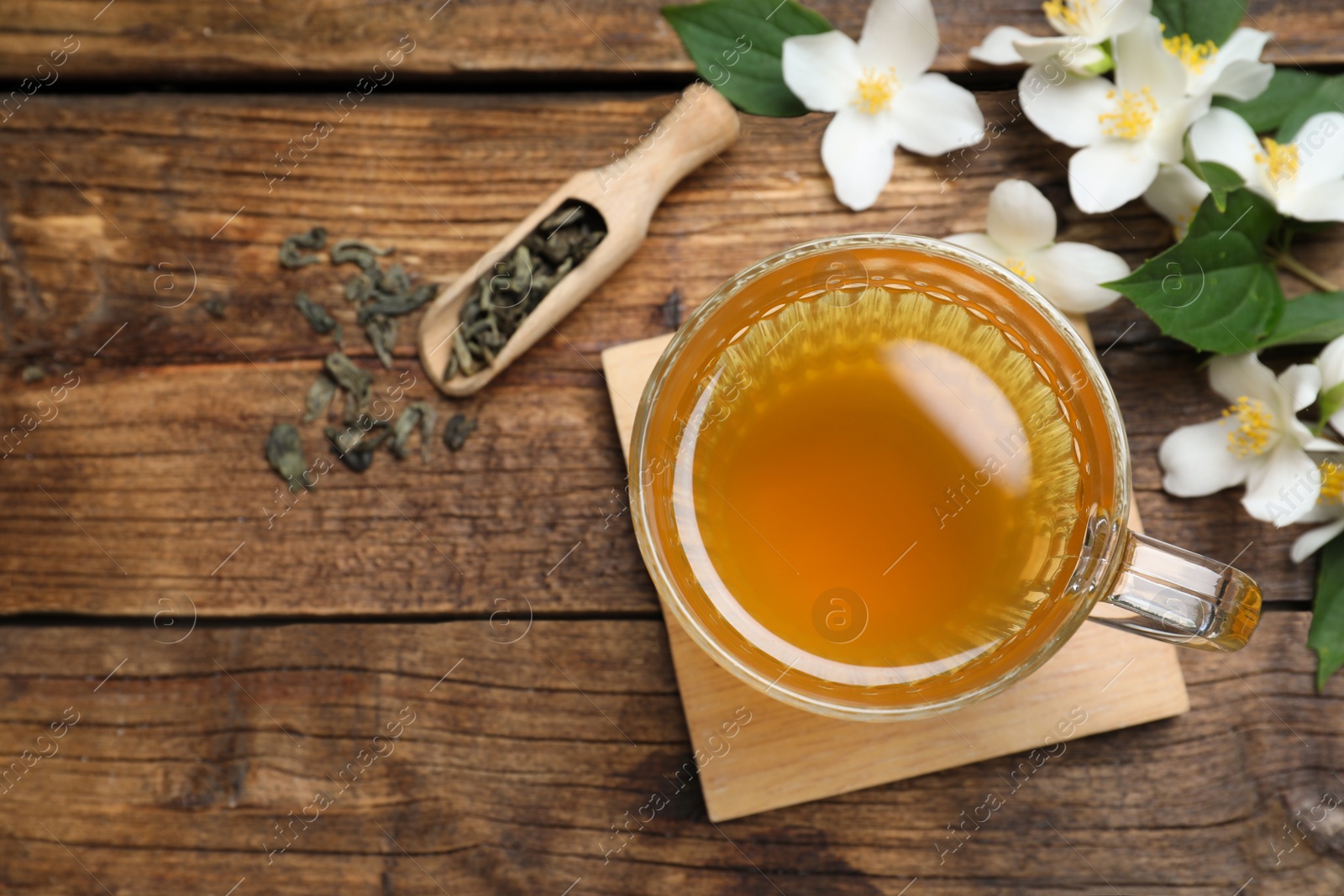 Photo of Cup of tea and fresh jasmine flowers on wooden table, flat lay. Space for text