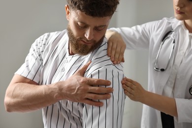 Sports injury. Doctor examining patient's shoulder in hospital, closeup