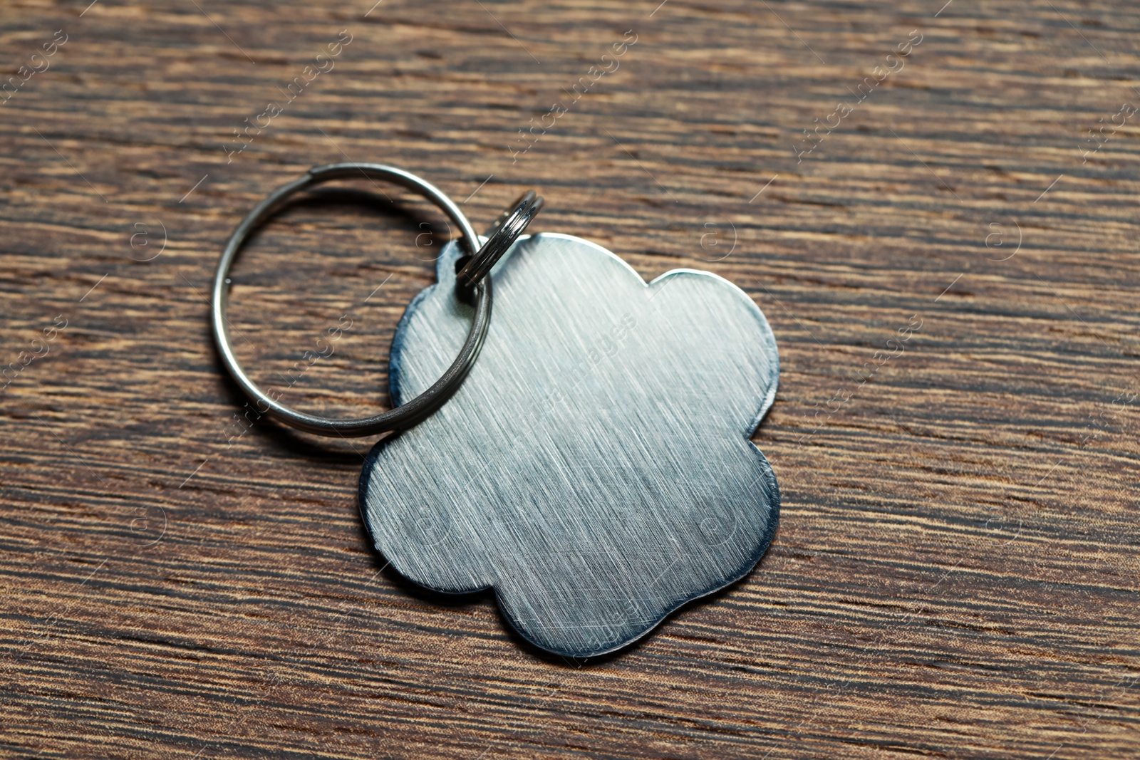 Photo of Silver pet tag with ring on wooden table, top view. Space for text