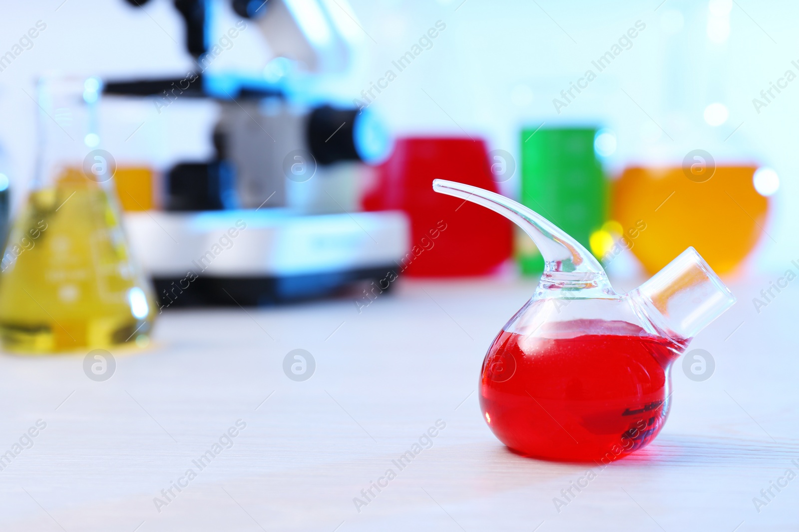 Photo of Retort flask with sample on table in chemistry laboratory, space for text