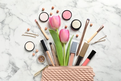 Photo of Many different makeup products and spring flowers on marble background, flat lay