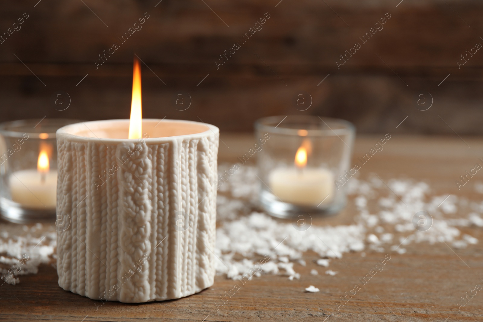 Photo of Candle and artificial snow on wooden table, space for text. Christmas decor