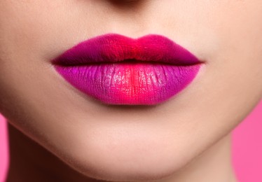 Photo of Young woman with beautiful lips makeup on pink background, closeup
