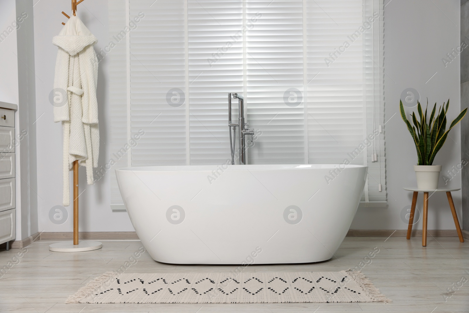 Photo of Stylish bathroom interior with ceramic tub and houseplant