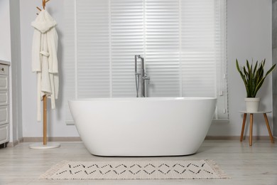 Stylish bathroom interior with ceramic tub and houseplant