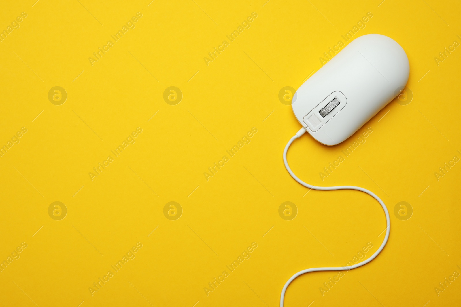 Photo of Wired computer mouse on yellow background, top view. Space for text