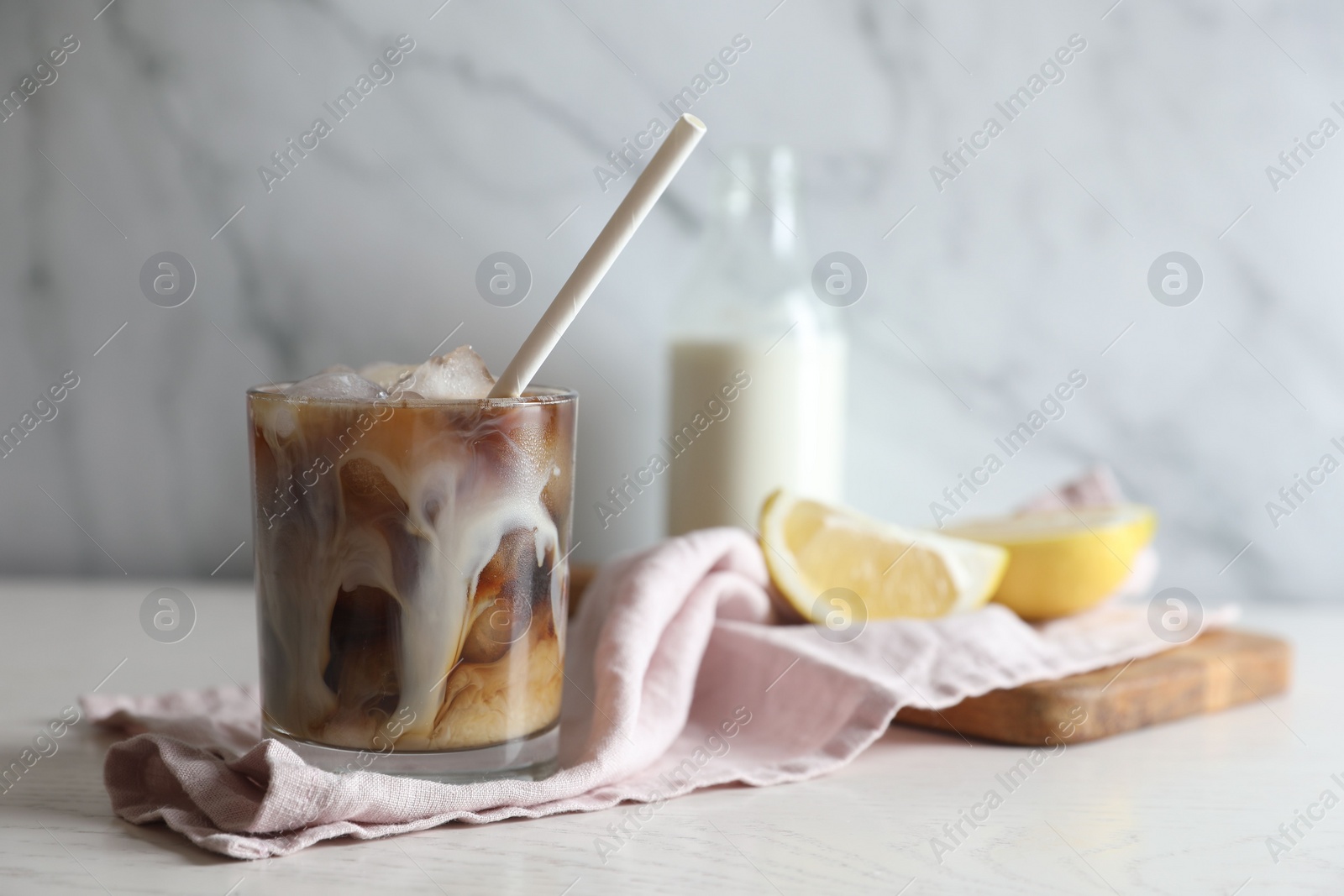 Photo of Refreshing iced coffee with milk in glass on white wooden table