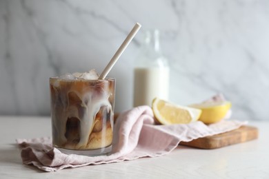 Photo of Refreshing iced coffee with milk in glass on white wooden table