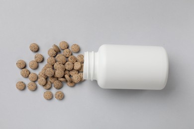 Vitamin pills and bottle on light grey background, top view