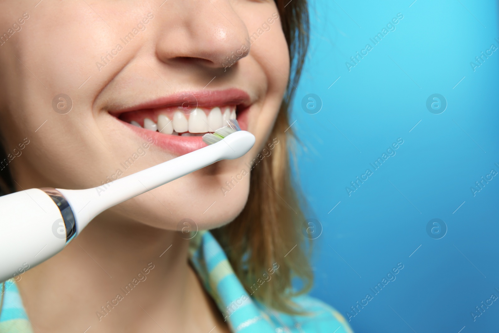 Photo of Young woman with electric toothbrush on color background, closeup. Space for text