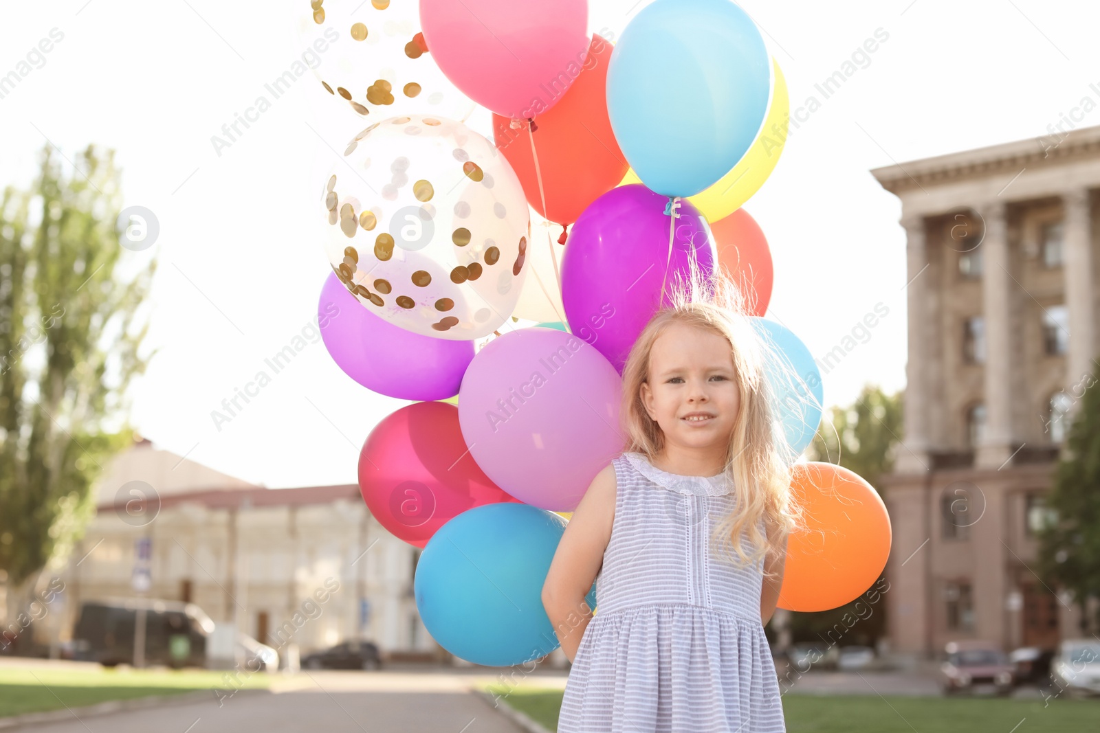 Photo of Cute little girl with colorful balloons outdoors on sunny day