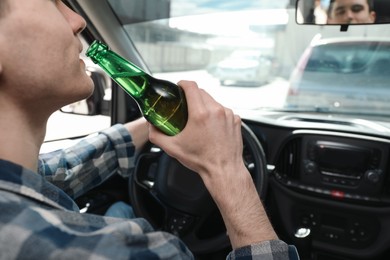 Photo of Man with bottle of beer driving car, closeup. Don't drink and drive concept