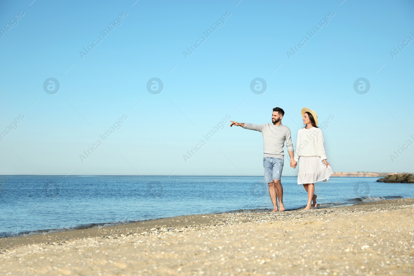 Photo of Happy young couple walking on beach near sea. Honeymoon trip