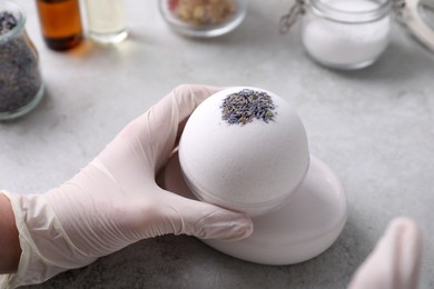 Woman in gloves with self made bath bomb at grey table, closeup