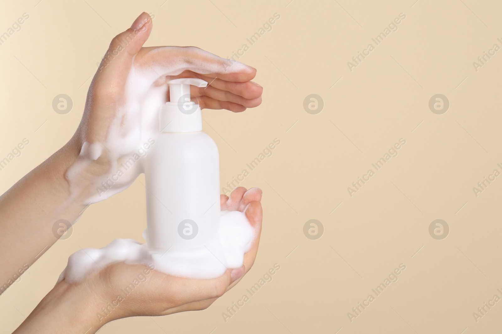 Photo of Woman with bottle of care product and cleansing foam on beige background, closeup. Space for text