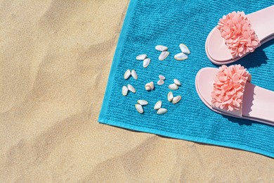Towel, flip flops and seashells on sand, above view. Beach accessories