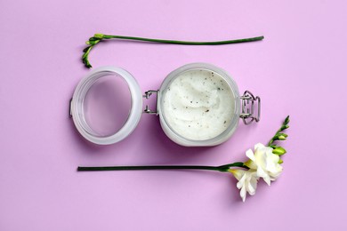 Photo of Body scrub and freesia flowers on pale violet background, flat lay