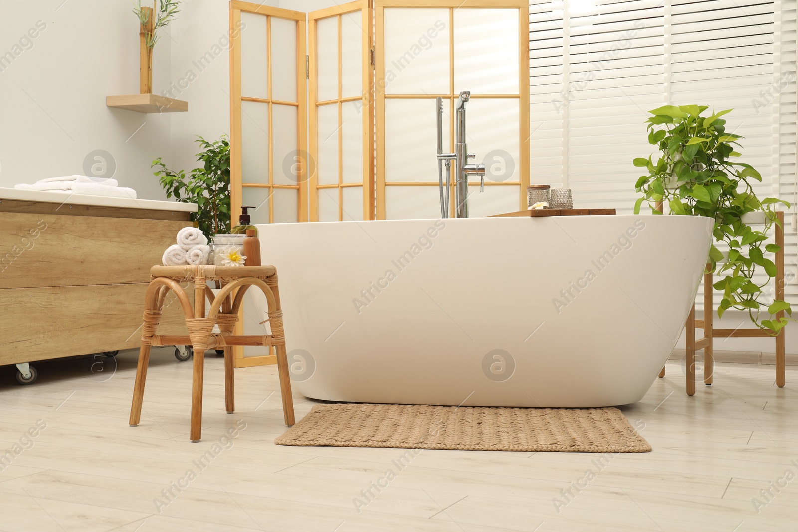 Photo of Stylish bathroom interior with ceramic tub, spa products and green houseplants