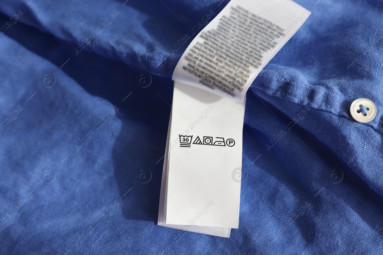 Photo of Clothing label in different languages on blue garment, closeup