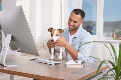 Photo of Young man with Jack Russell Terrier at desk in home office