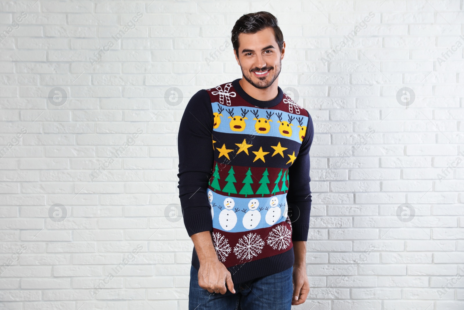 Photo of Portrait of happy man in Christmas sweater near white brick wall