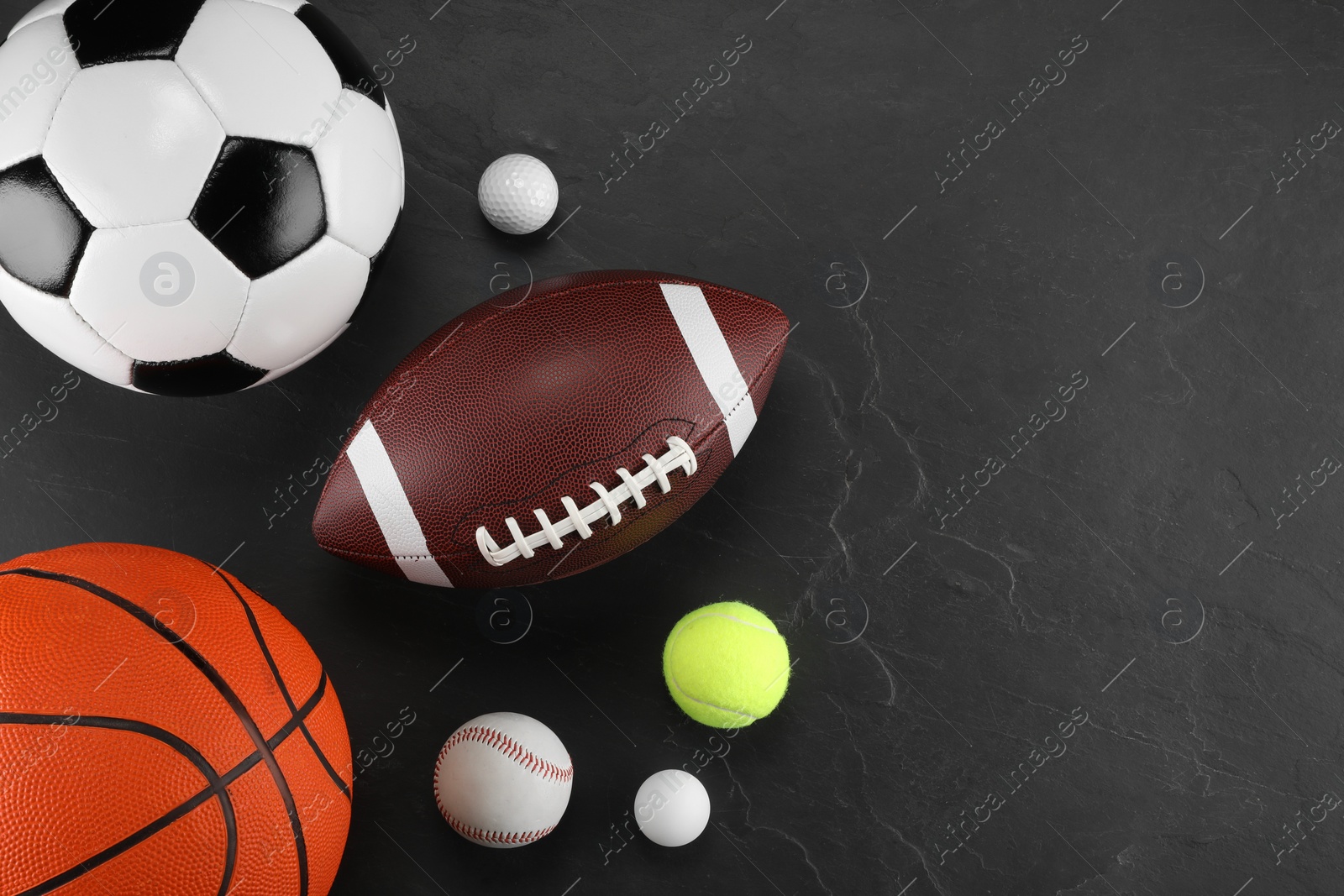 Photo of Many different sports balls on dark gray background, flat lay. Space for text