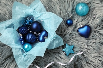 Photo of Beautiful Christmas baubles and box on grey faux fur, flat lay