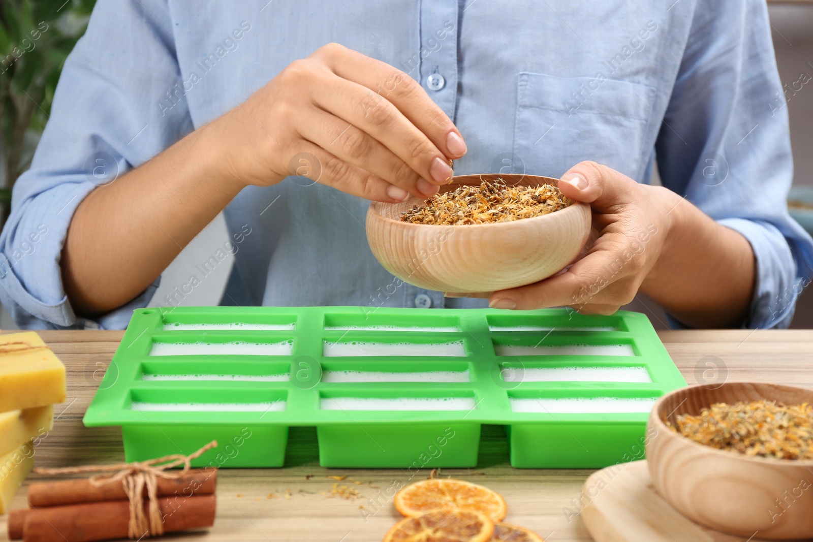 Photo of Woman making natural handmade soap at wooden table, closeup