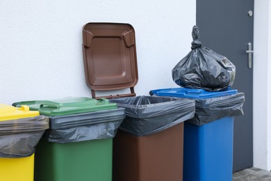 Photo of Plastic bag with garbage and recycling bins outdoors. Waste sorting