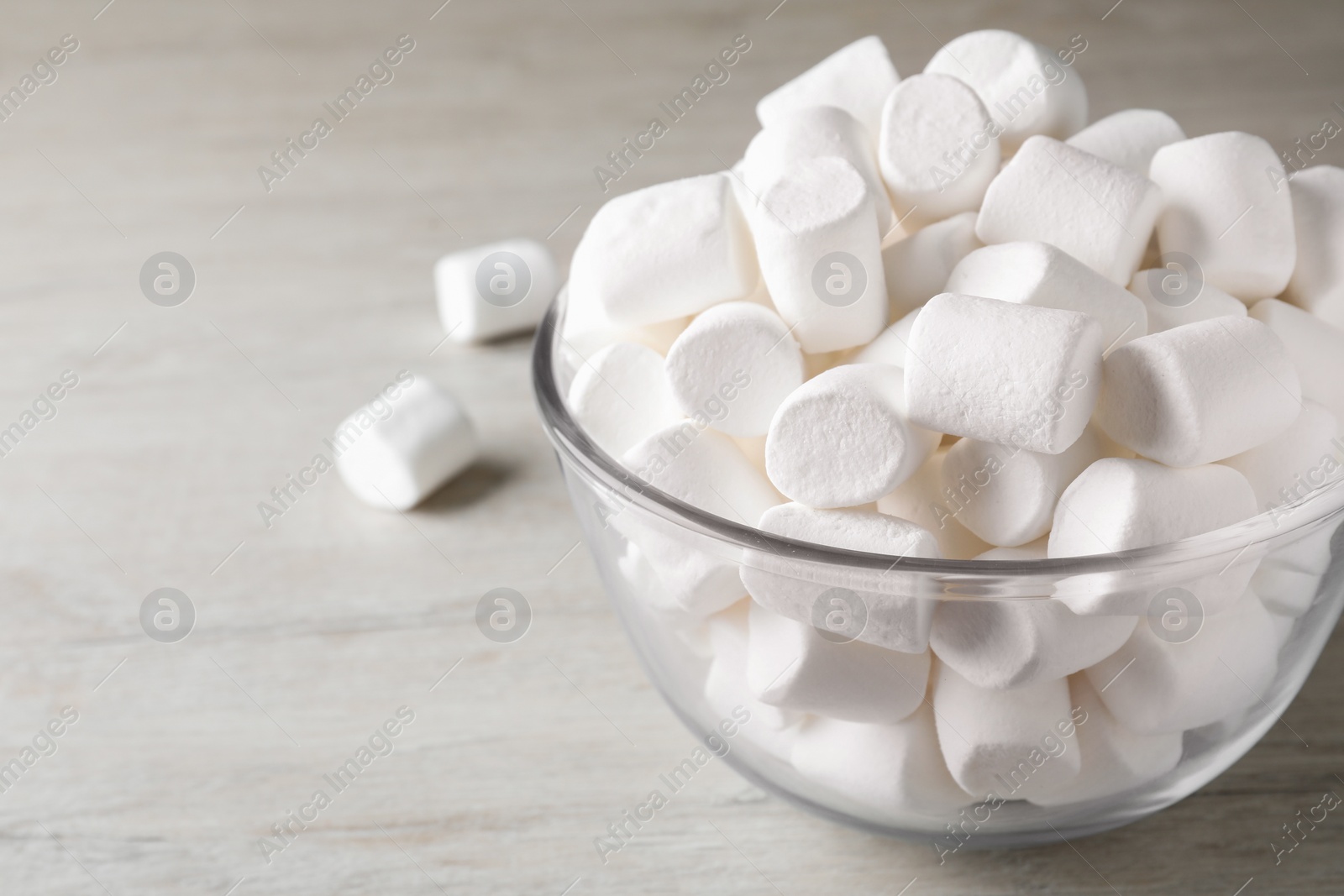 Photo of Delicious puffy marshmallows on wooden table, closeup. Space for text