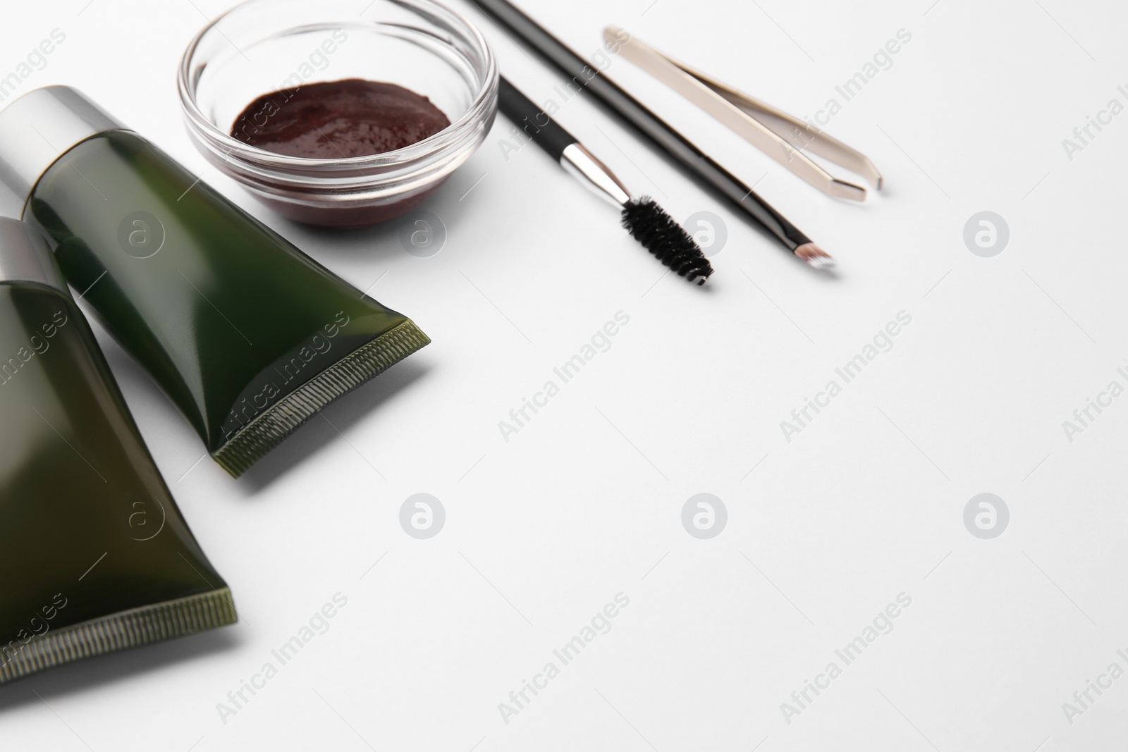 Photo of Eyebrow henna, professional tools and cosmetic products on white background, space for text