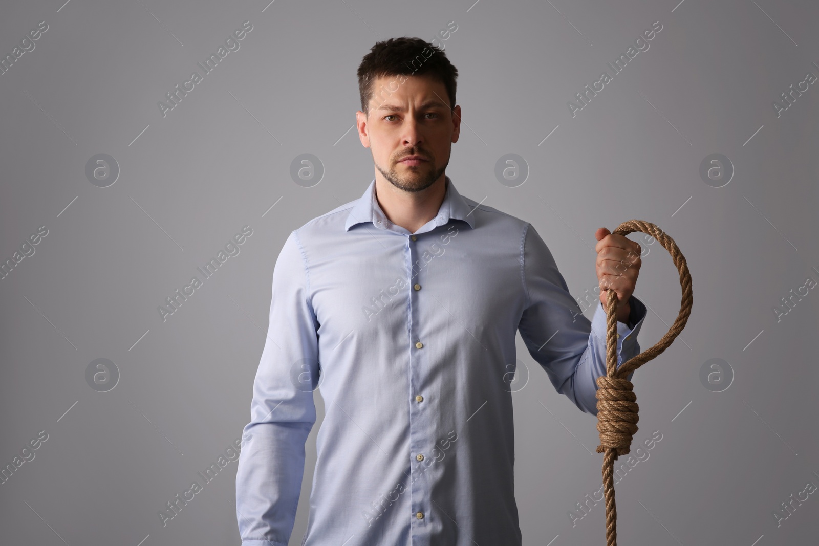 Photo of Depressed man with rope noose on light grey background