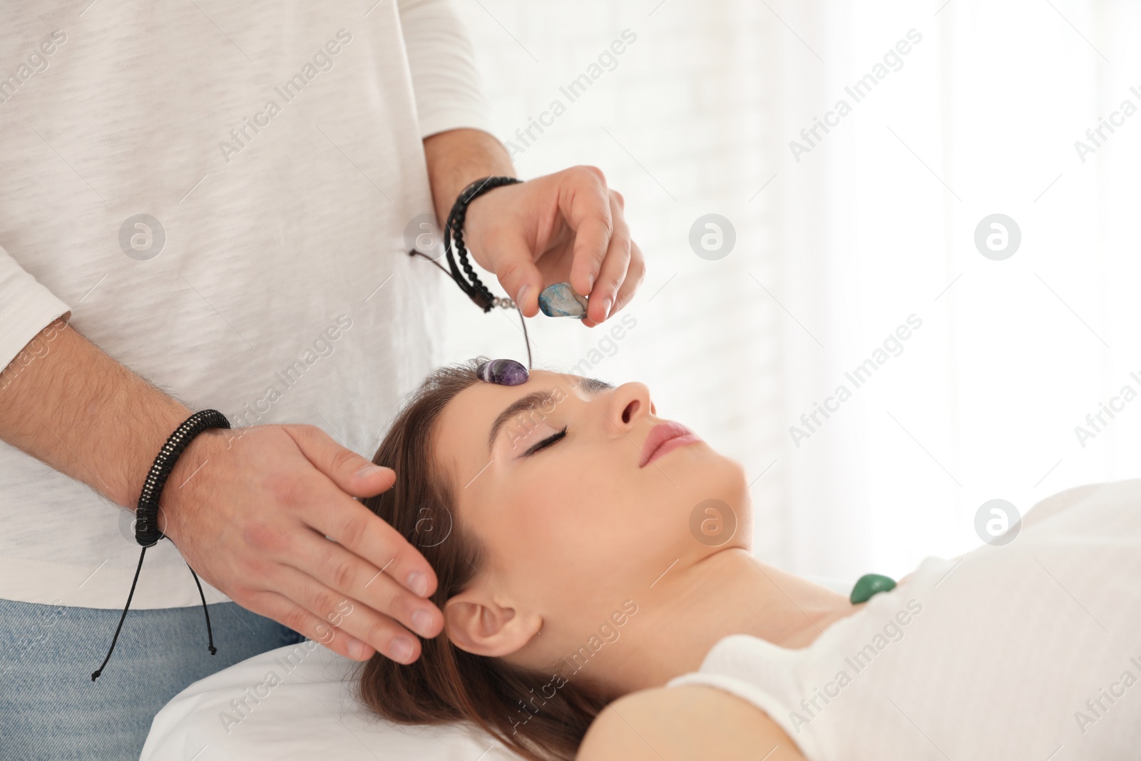 Photo of Young woman during crystal healing session in therapy room