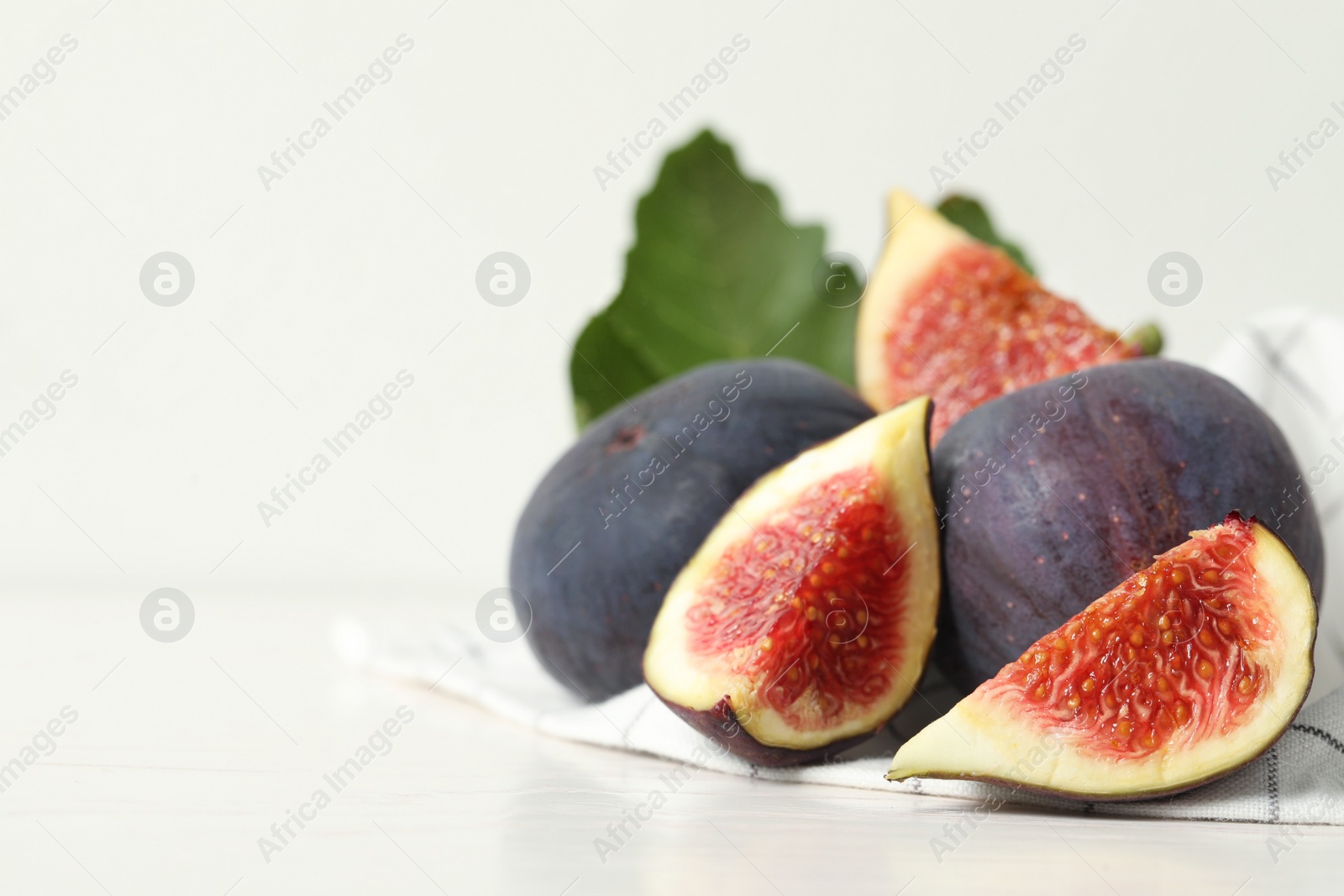 Photo of Whole and cut tasty fresh figs on white table, closeup. Space for text