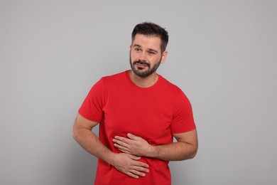 Man suffering from stomach pain on grey background