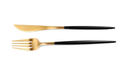 Photo of New golden fork and knife with black handles on white background, top view