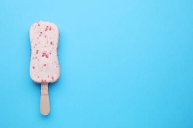 Delicious glazed ice cream bar on light blue background, top view. Space for text